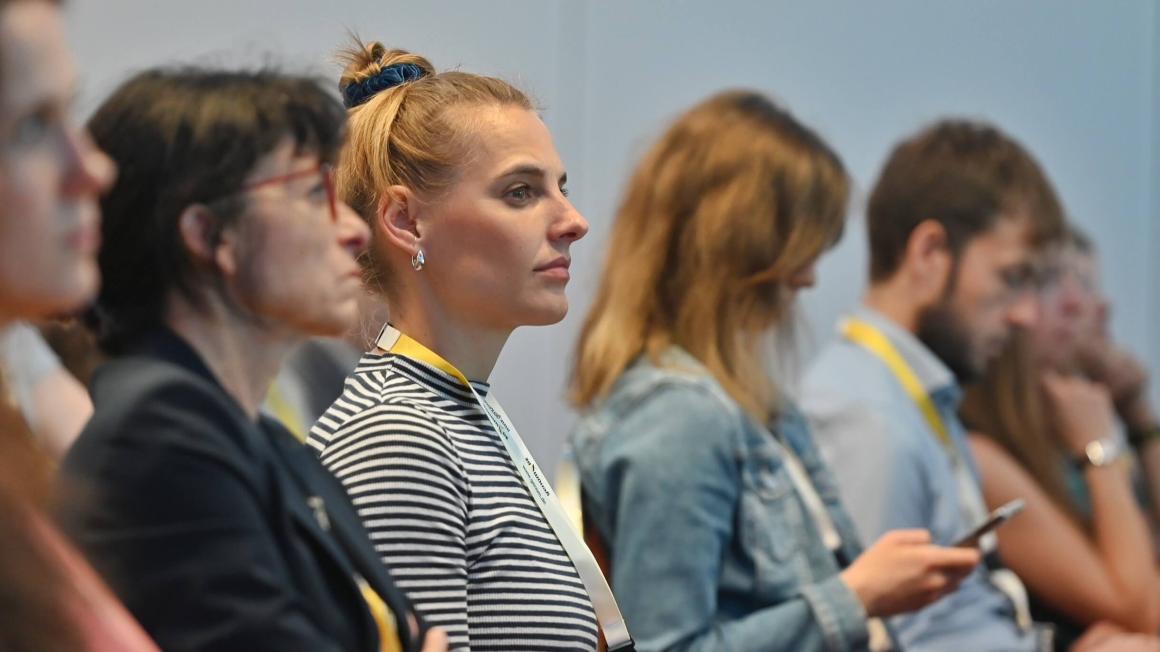 Das seitliche Profil von mehreren Personen aus dem Publikum des genomDE-Symposiums 2025